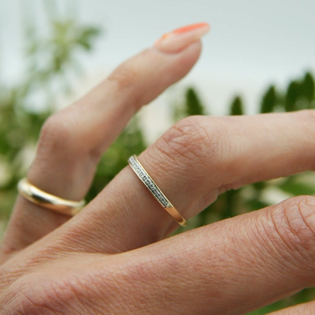 Two tone yellow gold and platinum thin pave wedding band on hand