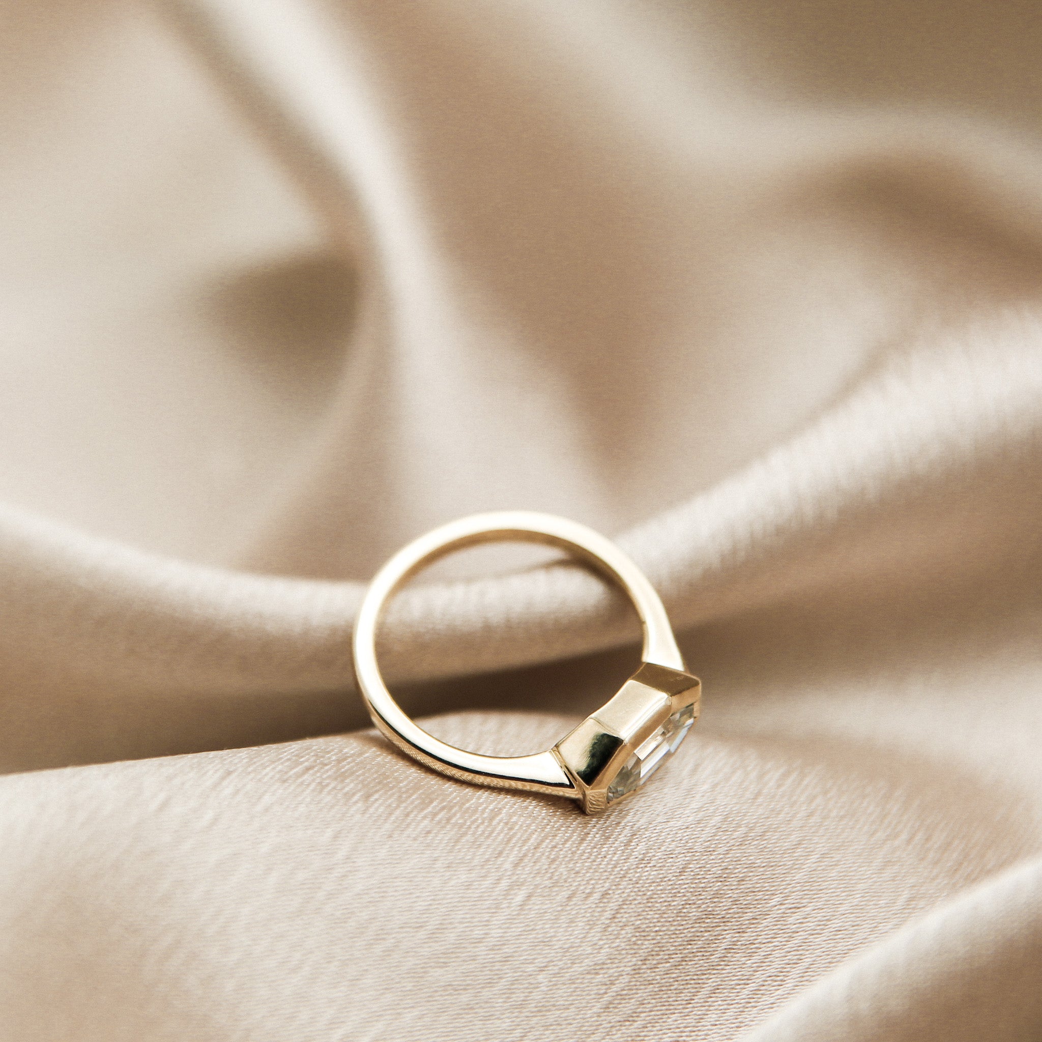 The perfect diamond engagement ring Milwaukees best jewelry store Cival Collective. Solid gold cast design is unique, modern and one of a kind. Faceted bezel set moissanite is a wonderful alternative to diamonds. Made by local Jewelry designers Re Frye and Nina Palacio. Gray Solitair is set east west with a custom cut step cut center stone