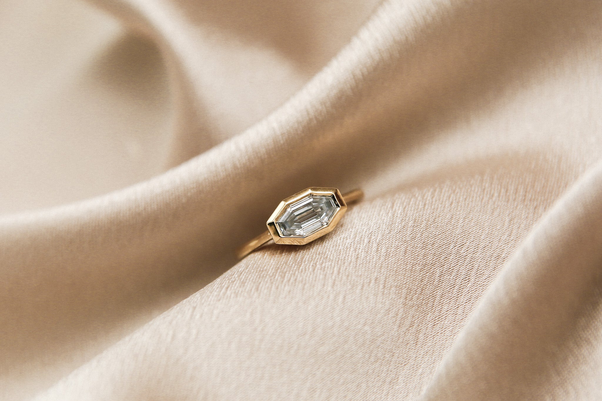 The perfect diamond engagement ring Milwaukees best jewelry store Cival Collective. Solid gold cast design is unique, modern and one of a kind. Faceted bezel set moissanite is a wonderful alternative to diamonds. Made by local Jewelry designers Re Frye and Nina Palacio. Gray Solitair is set east west with a custom cut step cut center stone