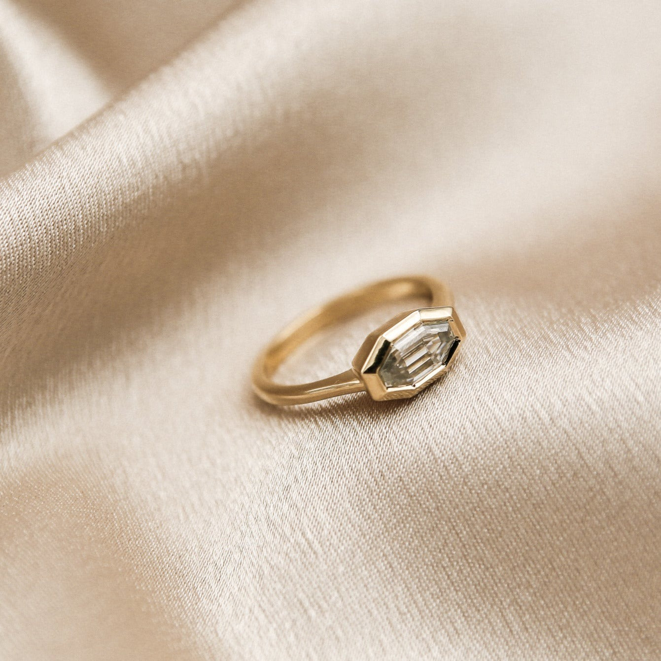 The perfect diamond engagement ring Milwaukees best jewelry store Cival Collective. Solid gold cast design is unique, modern and one of a kind. Faceted bezel set moissanite is a wonderful alternative to diamonds. Made by local Jewelry designers Re Frye and Nina Palacio. Gray Solitair is set east west with a custom cut step cut center stone