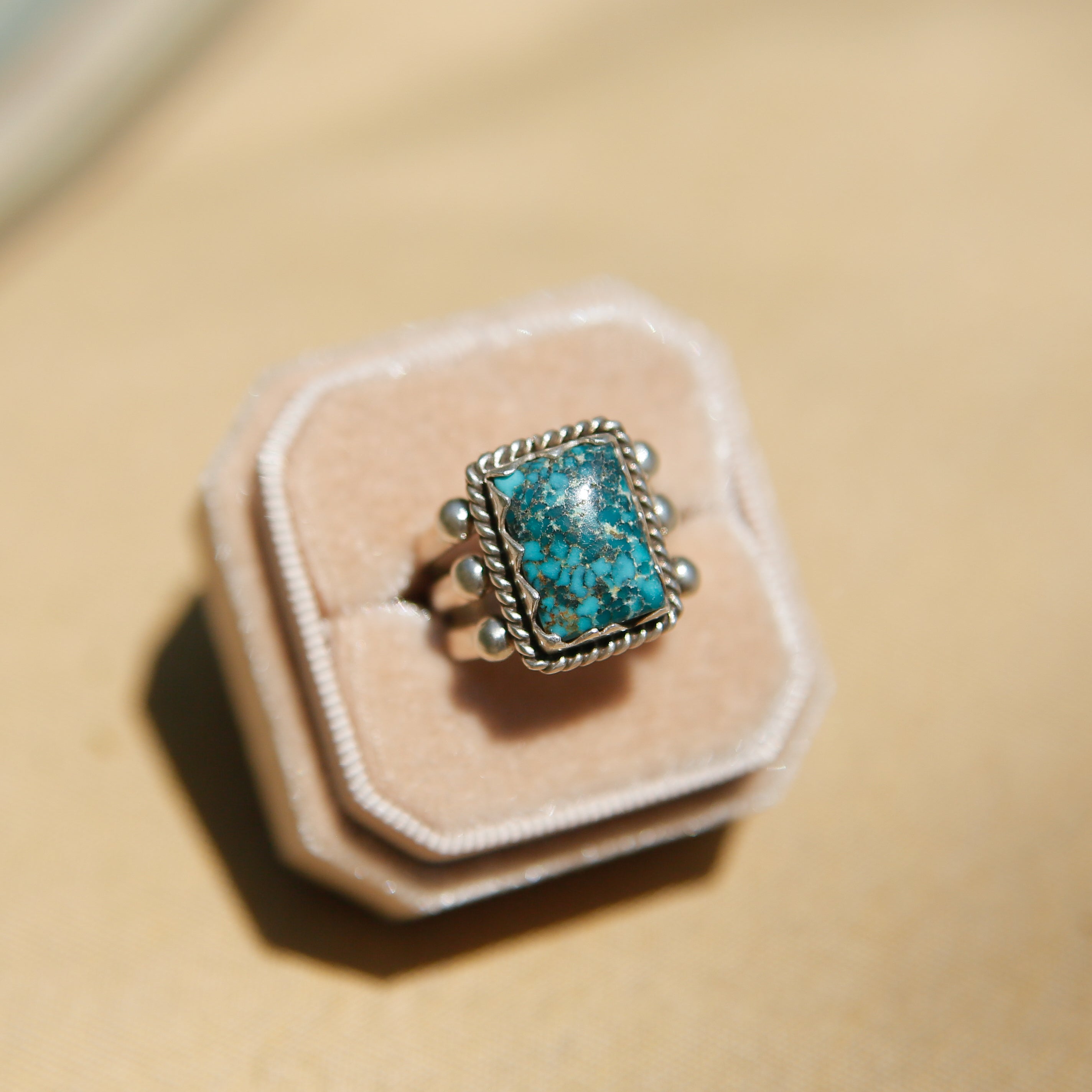Sterling silver 3 band ring with a rectangular turquoise stone. This ring has a bezel like setting made of sharp edges and a rope frame that has been patinated. Sold by Cival Collective in Milwaukee Wisconsin.