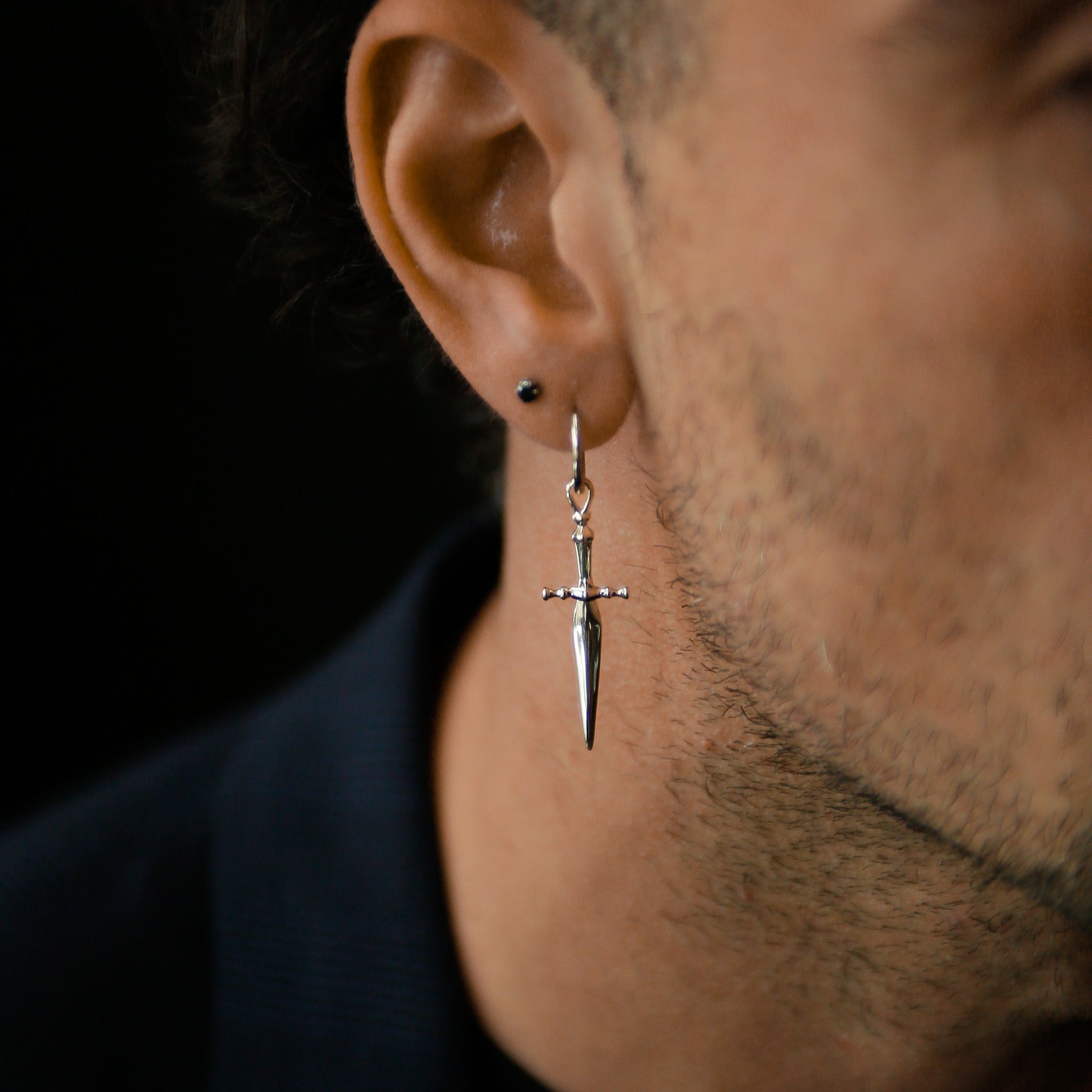Model wearing sterling silver hoop with sword dangling down.