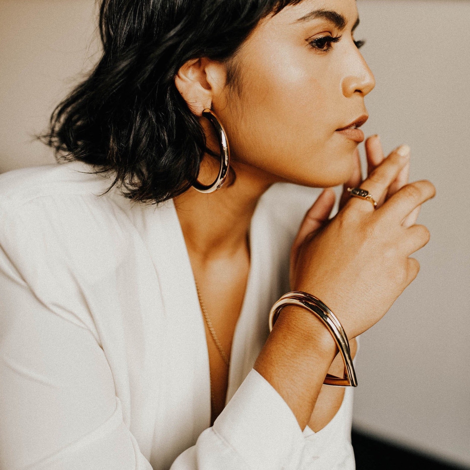 model wearing two stacked teardrop shaped brass bangles