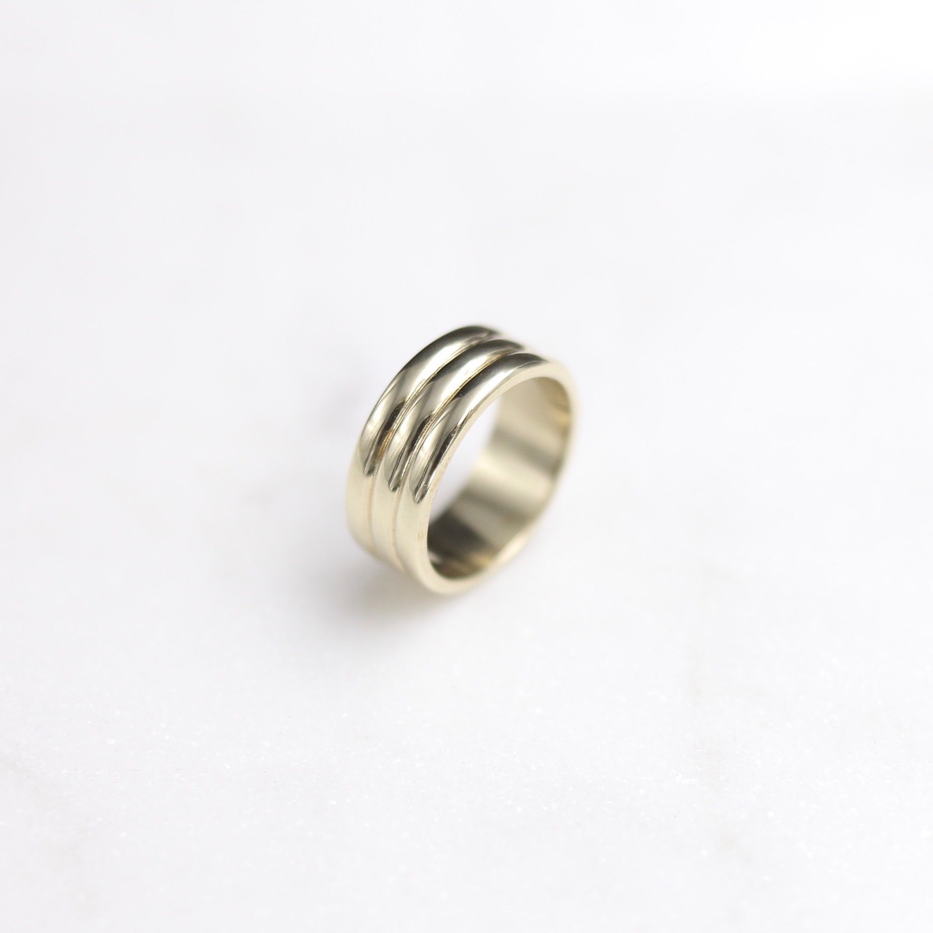 wide brass band with two east to west indents to make appearance of three stacked bands