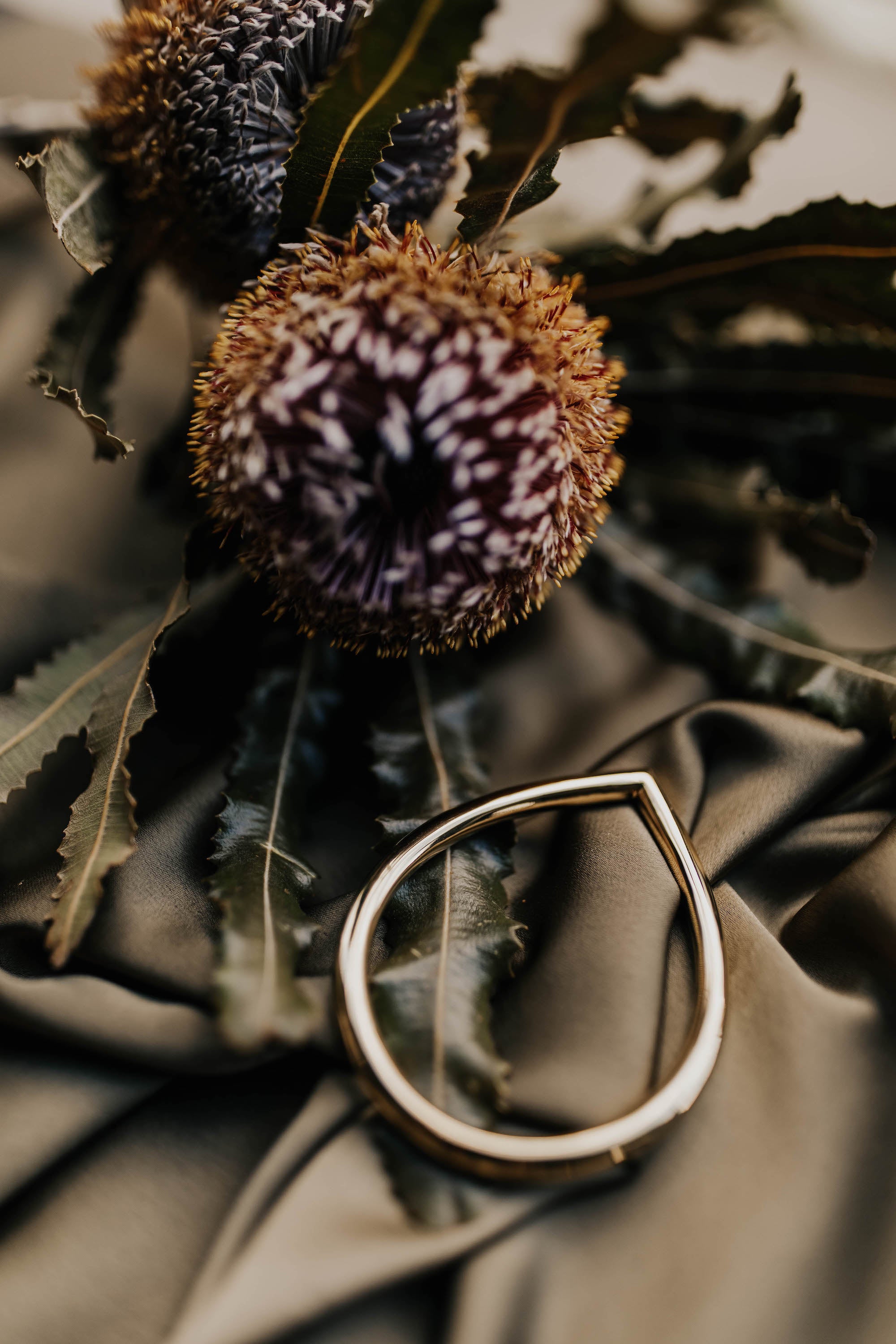 brass bangle next to purple and orange flower