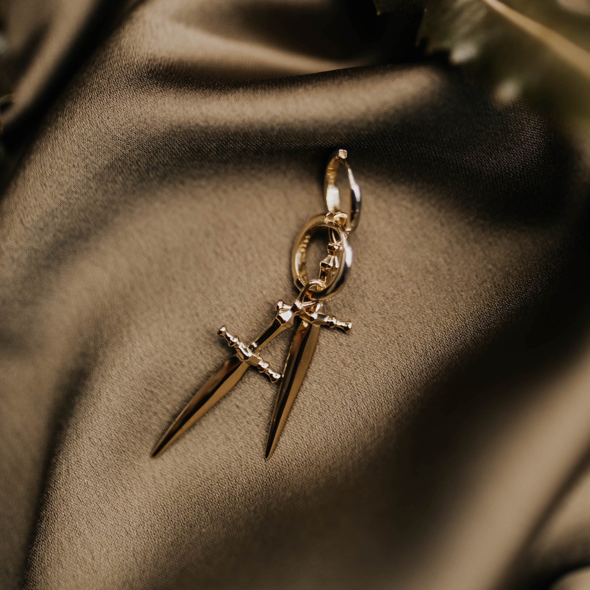 two brass hoop earrings with swords laid organically on top one another