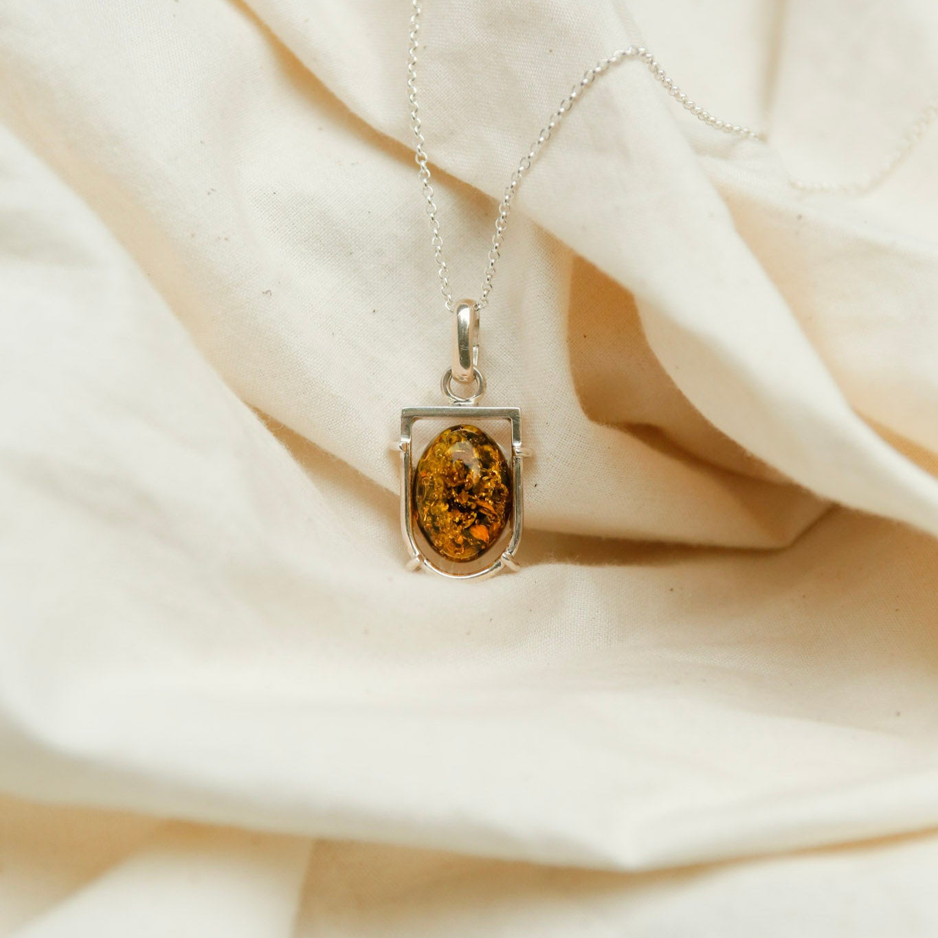 Silver vintage pendant with an amber stone set in a sterling silver arch. At Cival in Milwaukee Wisconsin