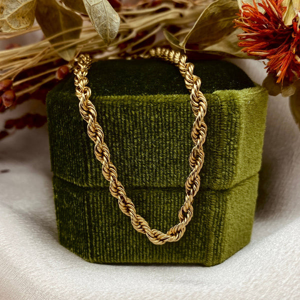 a 10k gold rope chain bracelet resting on a velvet box