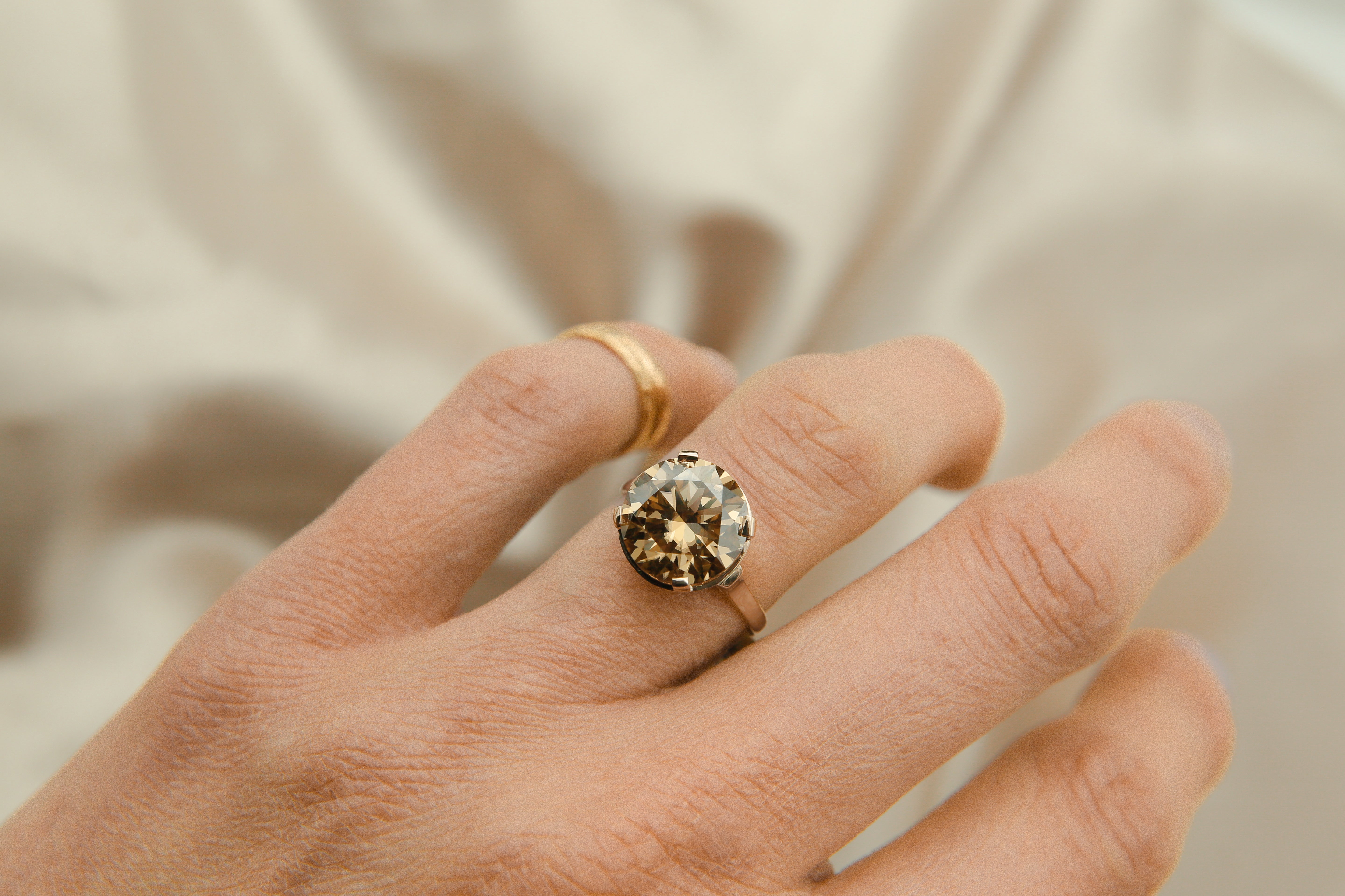 Model wearing 5ct sleek champagne moissanite ring with gold band 