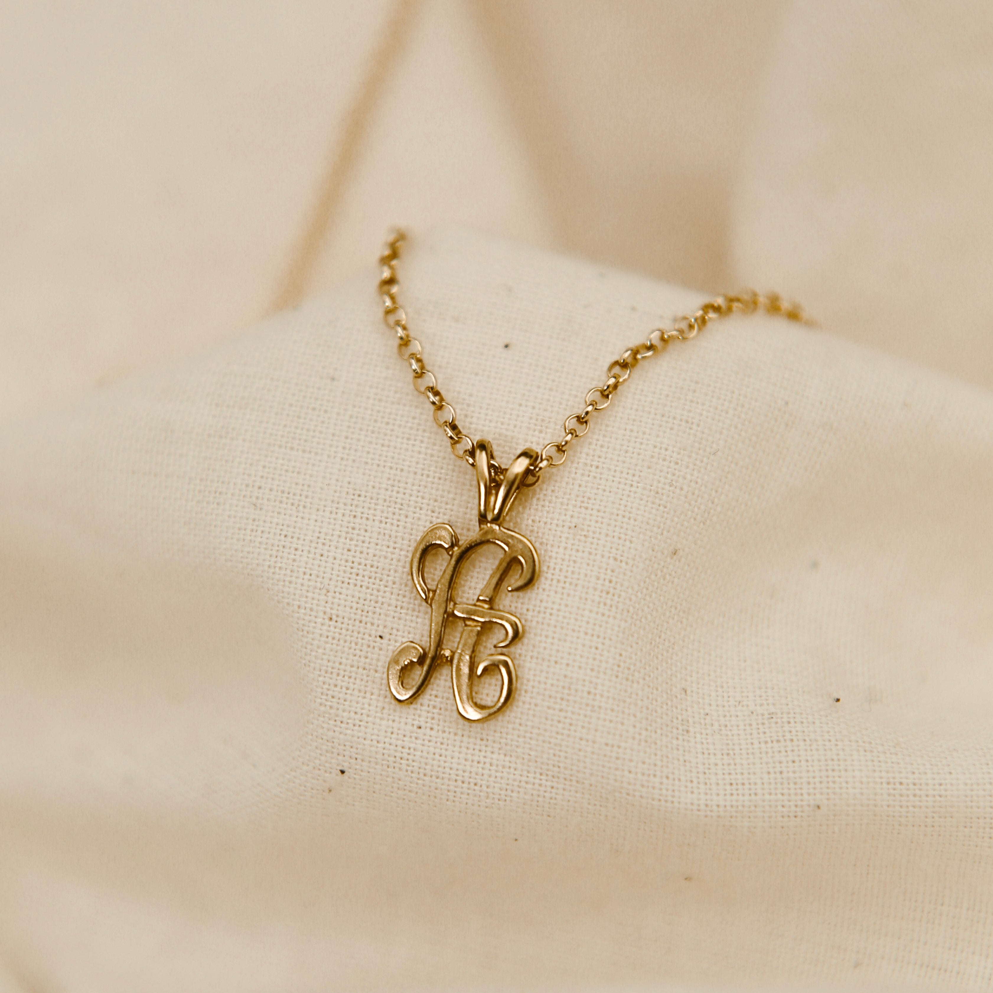 Gold necklace with a pendant on a beige fabric background