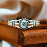 a sterling silver cuff with an ocean jasper center stone resting on a wooden box