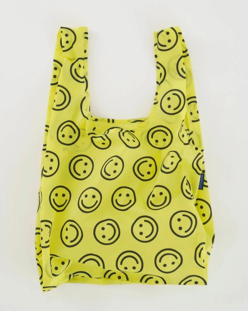 Open baggu standard size reusable bag in the yellow happy print colors are bright yellow and black smile face pattern