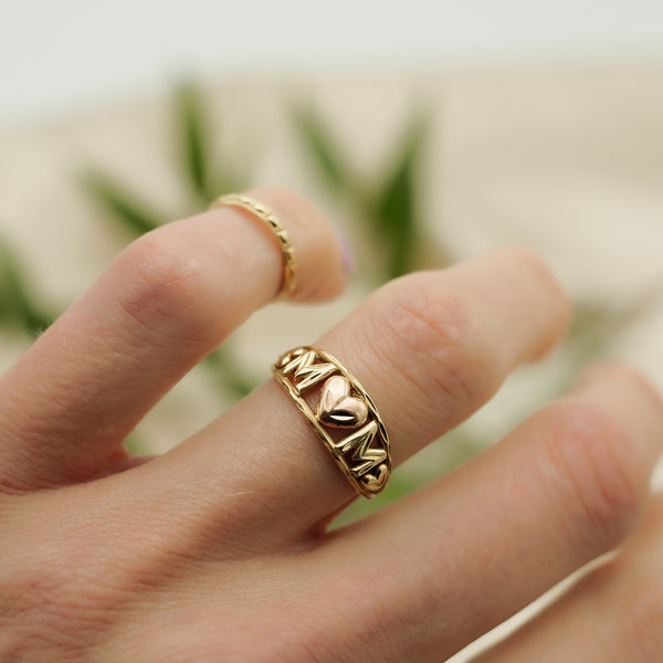 close up of 10k yellow gold mom love ring with rose gold heart detail on model. 
