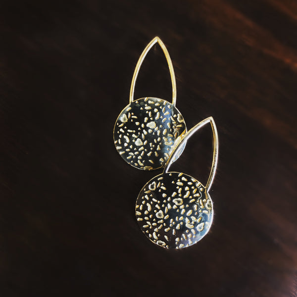 Detail of "Gwen" large brass cast teardrop stud earrings that have a textured brass circle at the bottom of the open teardrop shape.