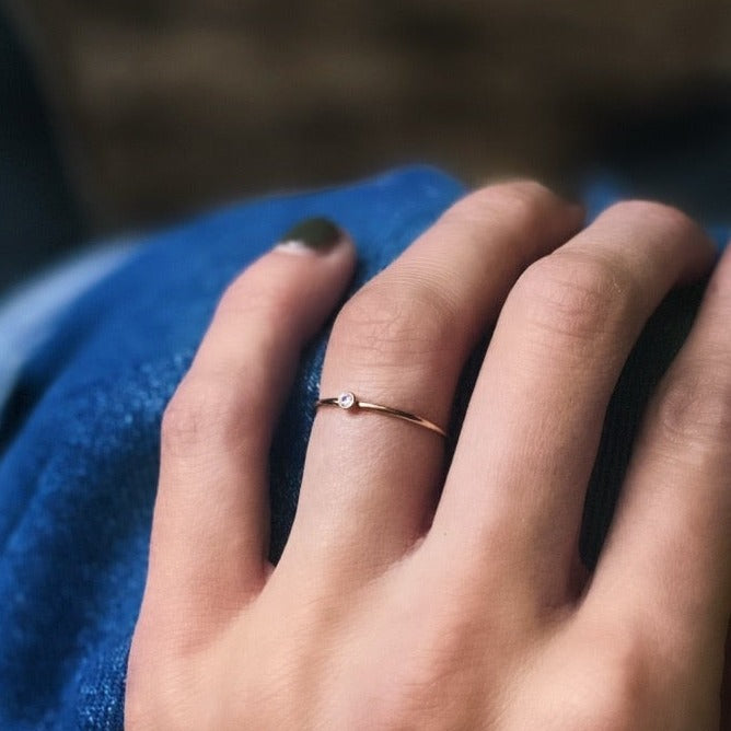 Model wearing gold stacking ring with small stone