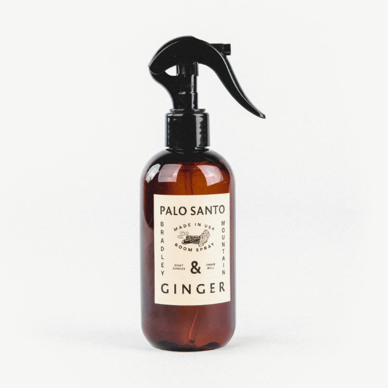 spray bottle with black plastic top and amber colored jar, labeled "palo santo and ginger" 