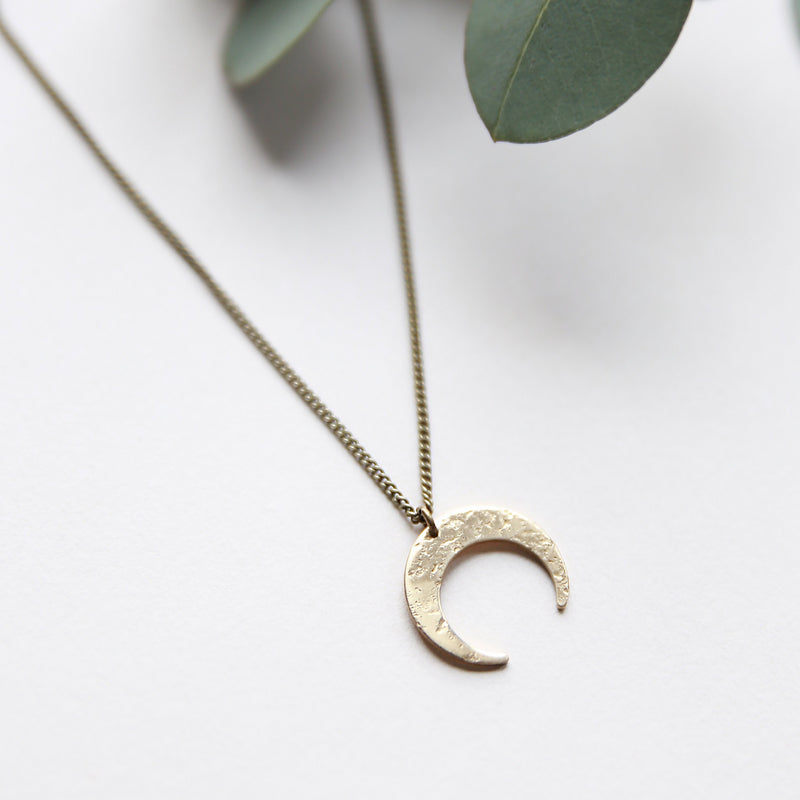 Delicate brass crescent moon necklace handmade by jewelry designers, Cival Collective.