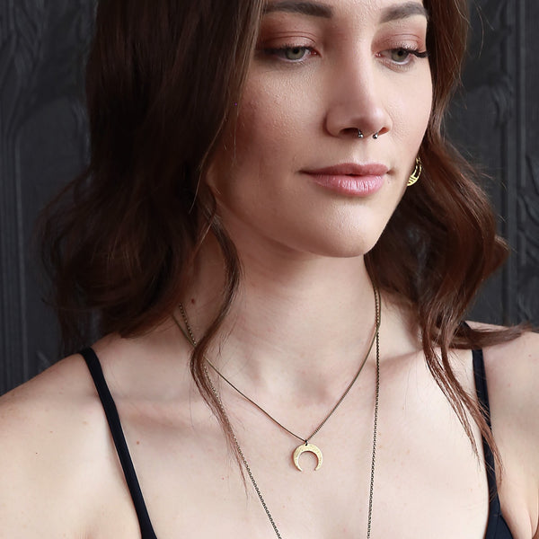 model wearing a cast brass crescent moon pendant on a brass chain