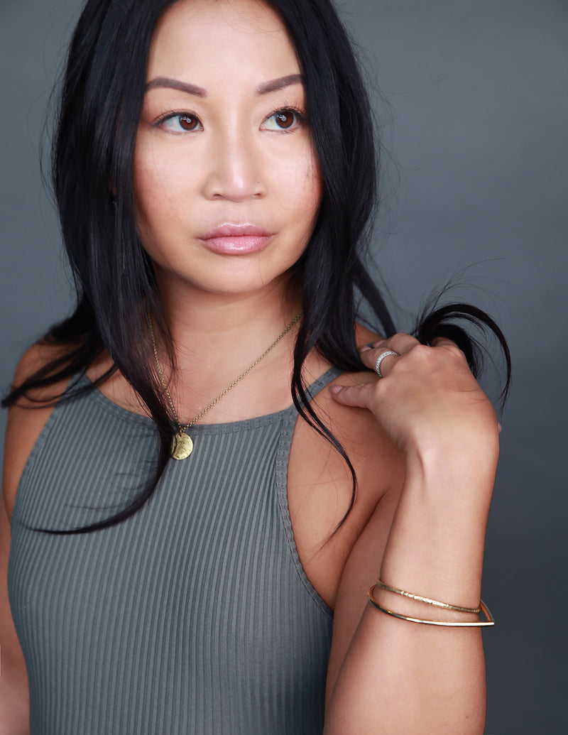 Model wearing handmade brass jewelry by designers Cival Collective.