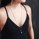Model wearing feather chain earrings and "Coco" brass capped stone necklace by CIVAL Collective.
