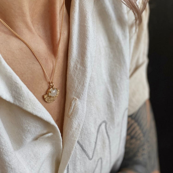 white moonstone cast brass pendant necklace on a woman's neck