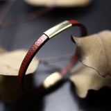Close up of "Aida" leather bracelet in blood orange leather and with a 1 inch brass slider in the middle.
