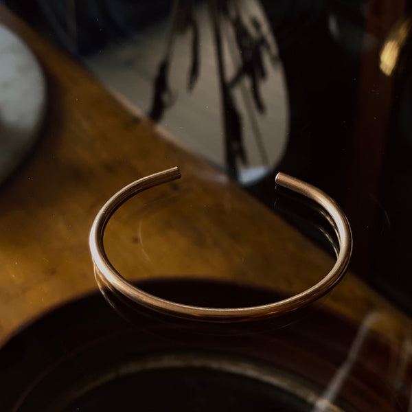 close up of a solid brass cuff with a minimalistic slim design.