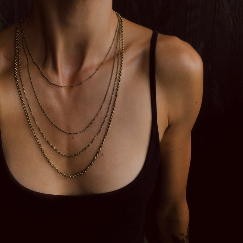 Collection of antique brass chain styles shown on model from CIVAL Collective.