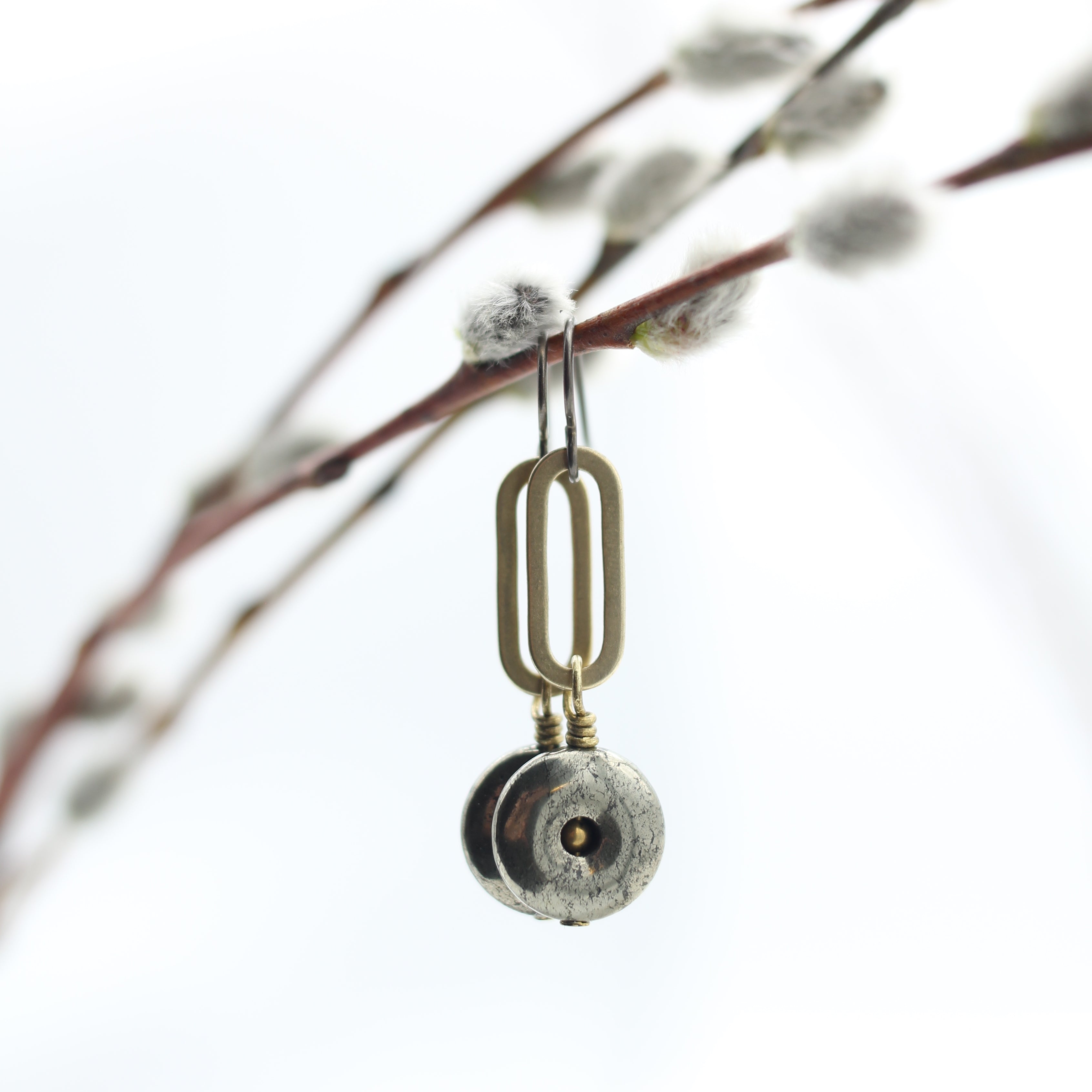 close up of drop earrings with pyrite donut at base