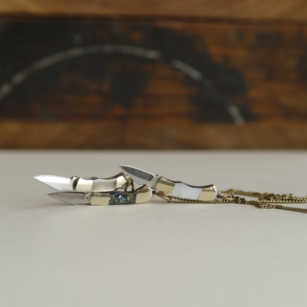 three brass plated knives with  grey mother of pearl, white mother of pearl and abalone inlay bodies on brass chains