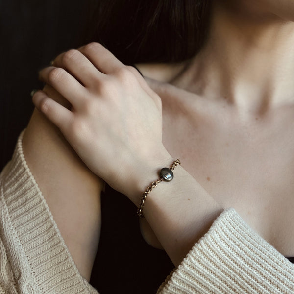 close up of a brass chain bracelet with a pyrite accent stone on a model's wrist  