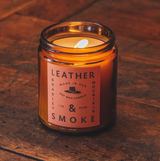 Lit candle in amber colored jar, labeled leather and smoke 