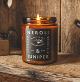 lit candle in amber colored jar, labeled "neroli and juniper" 