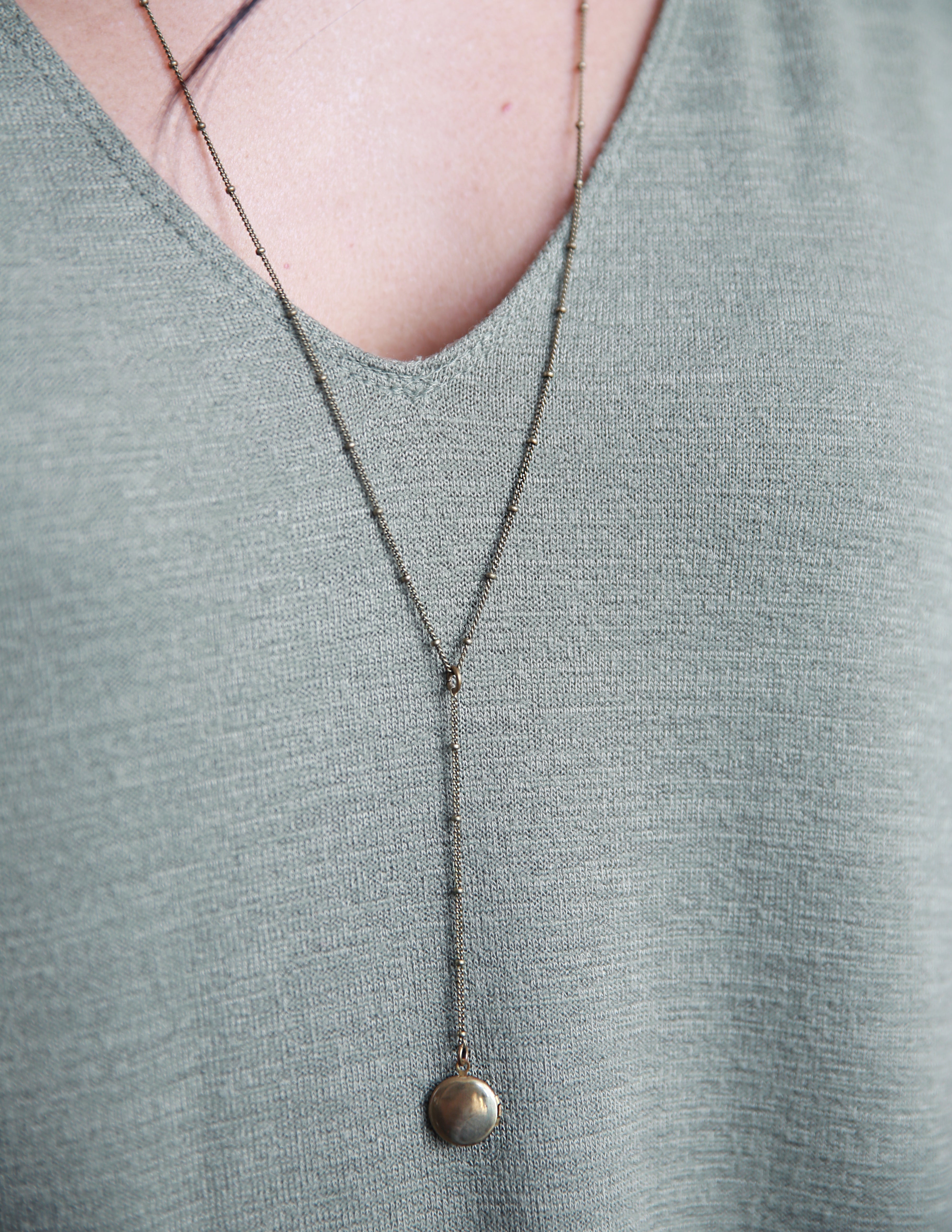 CIVAL Collective's "Vie" rosary style necklace on model that is 24 inches long and has a 2 inch drop with little brass locket at the end.