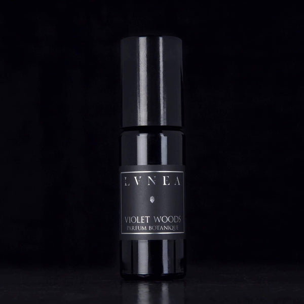 black perfume bottle on black background. product labeled "LVNEA" violet woods, perfume botanique 
