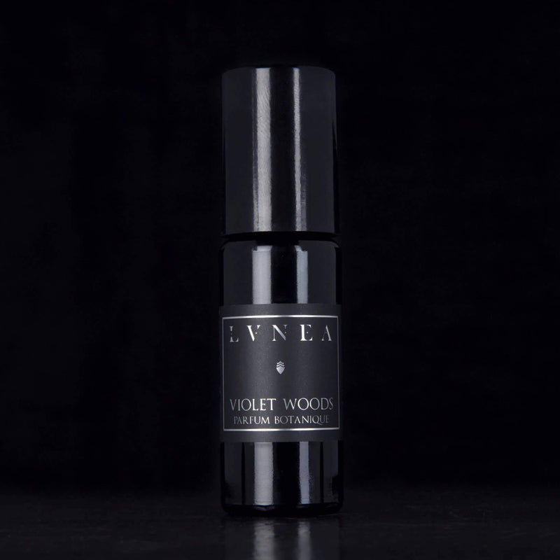 black perfume bottle on black background. product labeled "LVNEA" violet woods, perfume botanique 