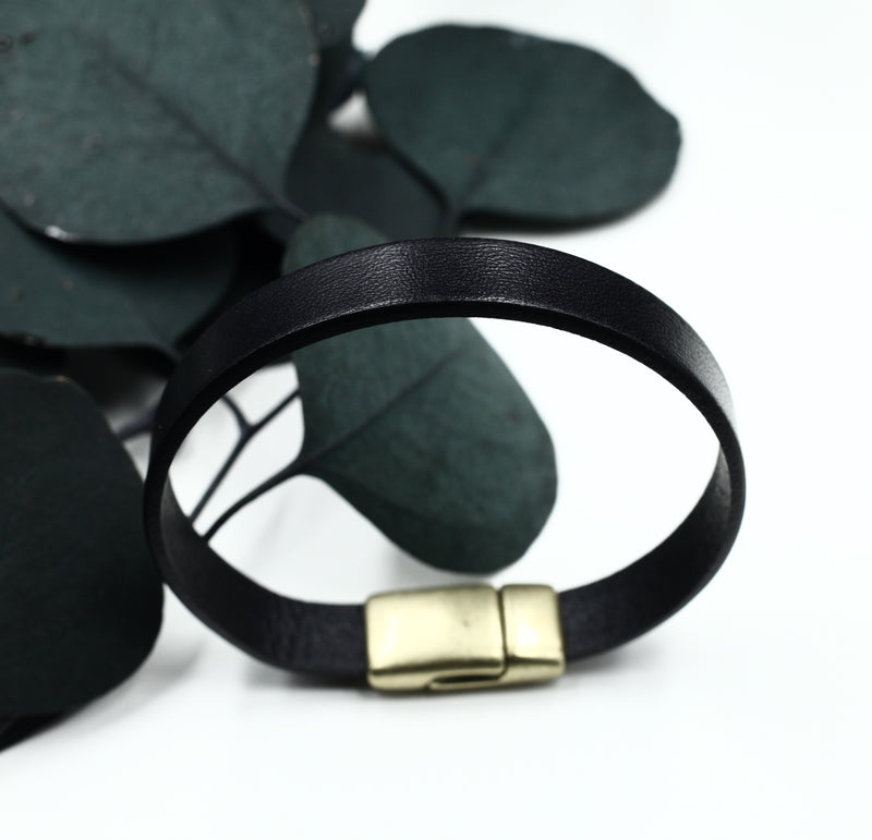 Black wide leather bracelet with magnetic brass clasp displayed upright on white background.
