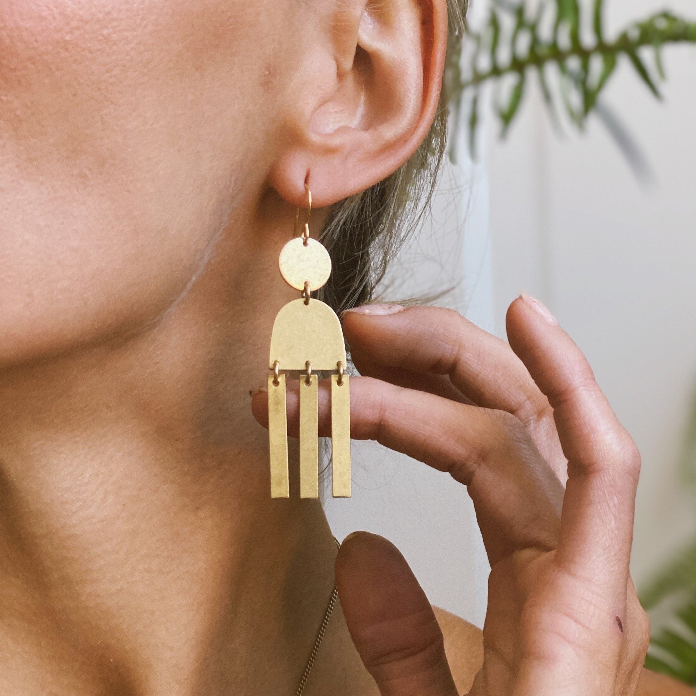 Close up of CIVAL's geometric stack brass "Alana" earrings.