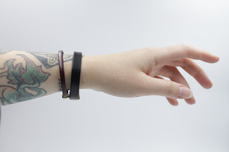 CIVAL Collective's "Aime" bracelet in mahogany leather and "Acer"  bracelet in black leather layered together on model's wrist. 