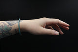 Model's wrist wearing CIVAL Collective's turquoise leather "Aime" bracelet with magnetic clasp.