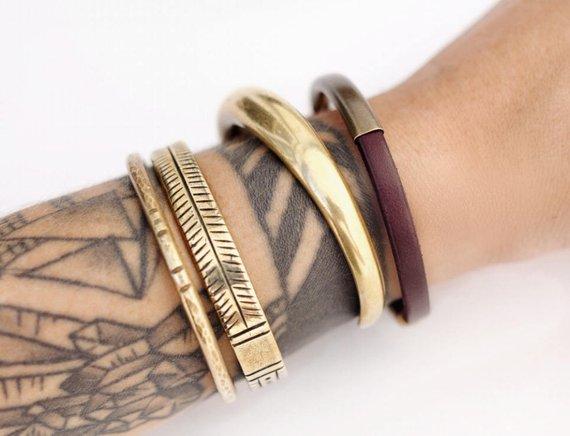 Three brass bracelets and an "Aster" mahogany leather bracelet on model's wrist.
