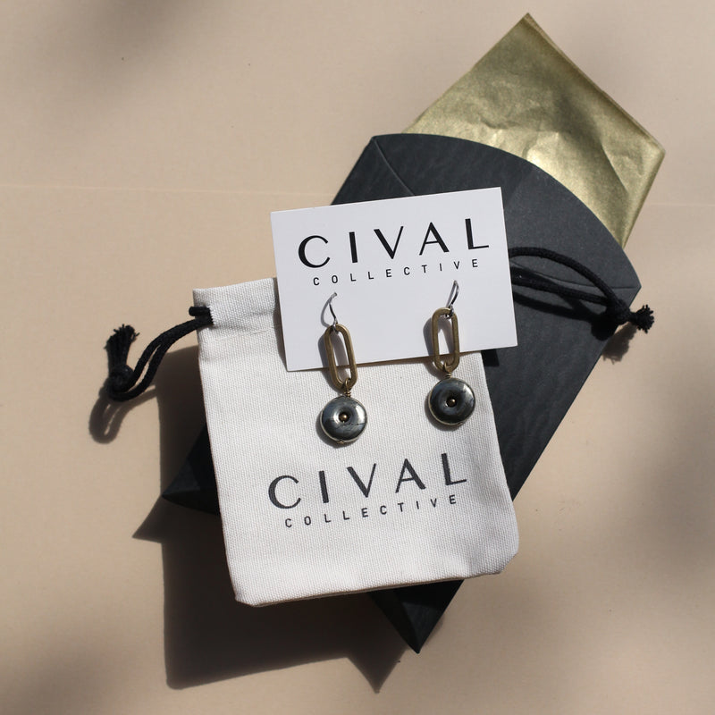 image of earrings by cival collective resting on a cloth jewelry bag and gift packaging