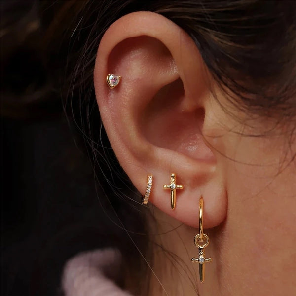 gold fill sword piercing, a stud, and a hoop on a woman's ear