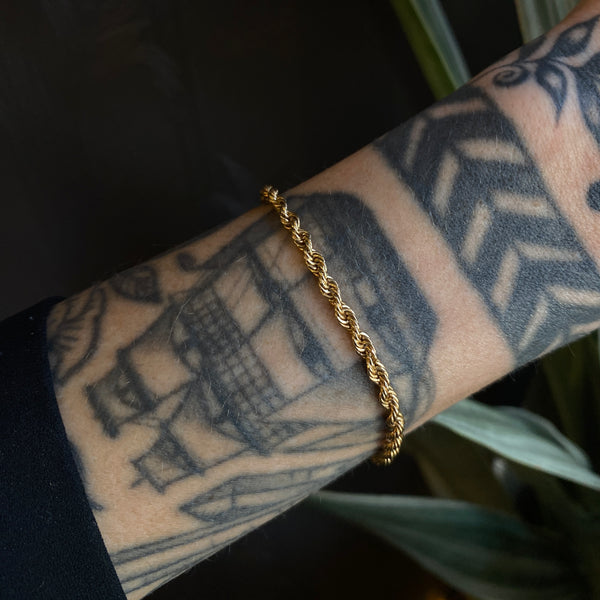 a 14k yellow gold rope chain bracelet on a model's wrist 