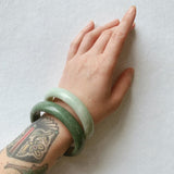 two jade bangles layered on a woman's wrist