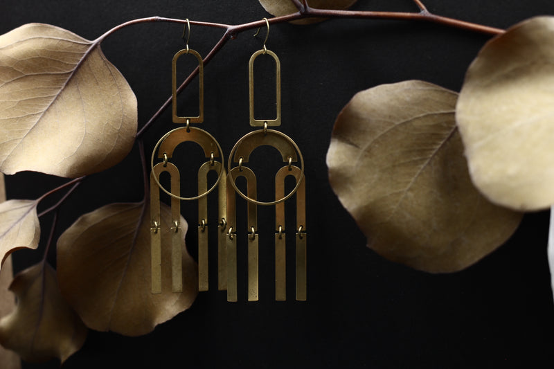 Bright brass "Joni" statement earrings made up of modern brass shapes stacked and connected with jump rings creating a chandelier look.