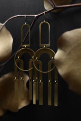Detail of bright brass "Joni" statement earrings made up of modern brass shapes stacked and connected with jump rings creating a chandelier look.