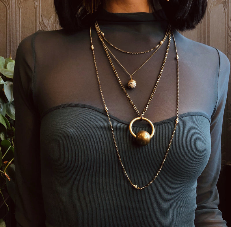 Three necklace layering set including two Dalmatian jasper necklaces & a brass sphere suspension necklace. Pictured on model from CIVAL Collective in Milwaukee WI.