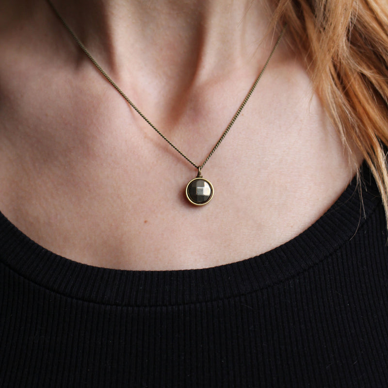 Necklace featuring a faceted pyrite set in a brass ring on a model in Cival Collective