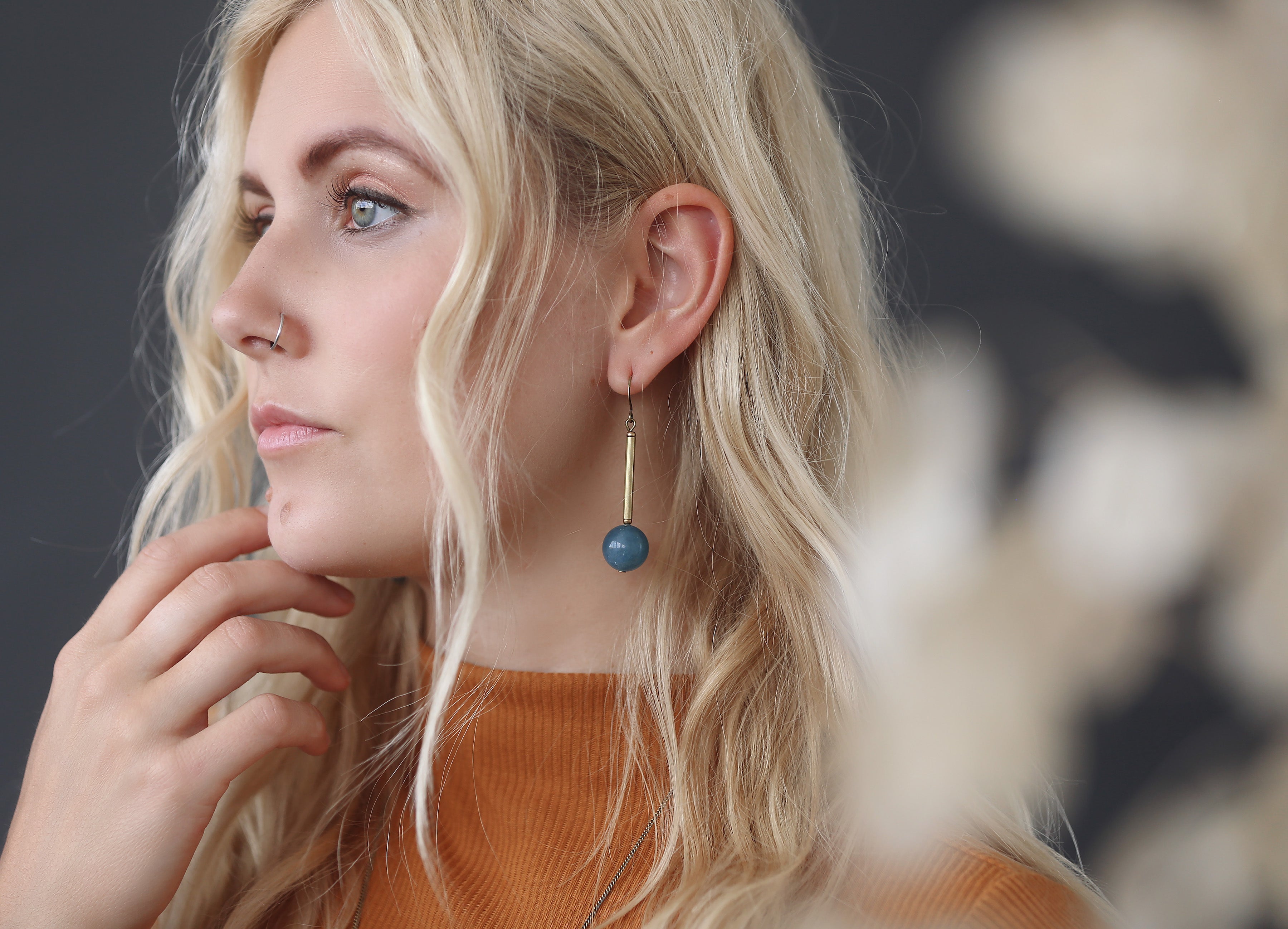 Model wearing CIVAL Colelctive's "Marit" drop earrings with brass bar and blue angelite round.